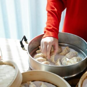 Person preparing handmade dumplings in a kitchen setting, focusing on the culinary process.